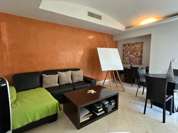 Casa en venta en lagos del sol cancun - Sala de estar con sofá, mesa de centro y caballete en un ambiente luminoso