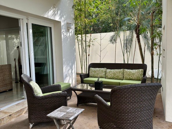 Casa en venta en lagos del sol cancun - Acogedor espacio en el exterior con muebles de mimbre oscuro rodeado de palmeras