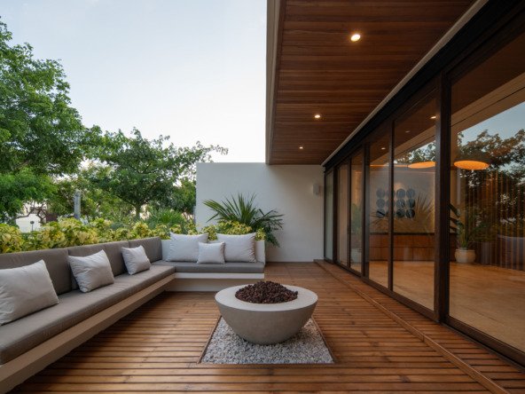 Casa en venta en puerto cancún - Amplia terraza exterior con piso de madera, un sofá en L y una moderna fogata central