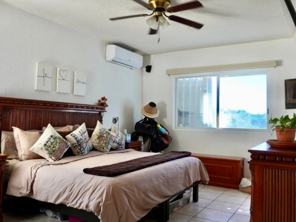 Departamento en venta en centro cancún - Recámara con cama grande y mobiliario de madera tradicional.. Iluminada con luz natural