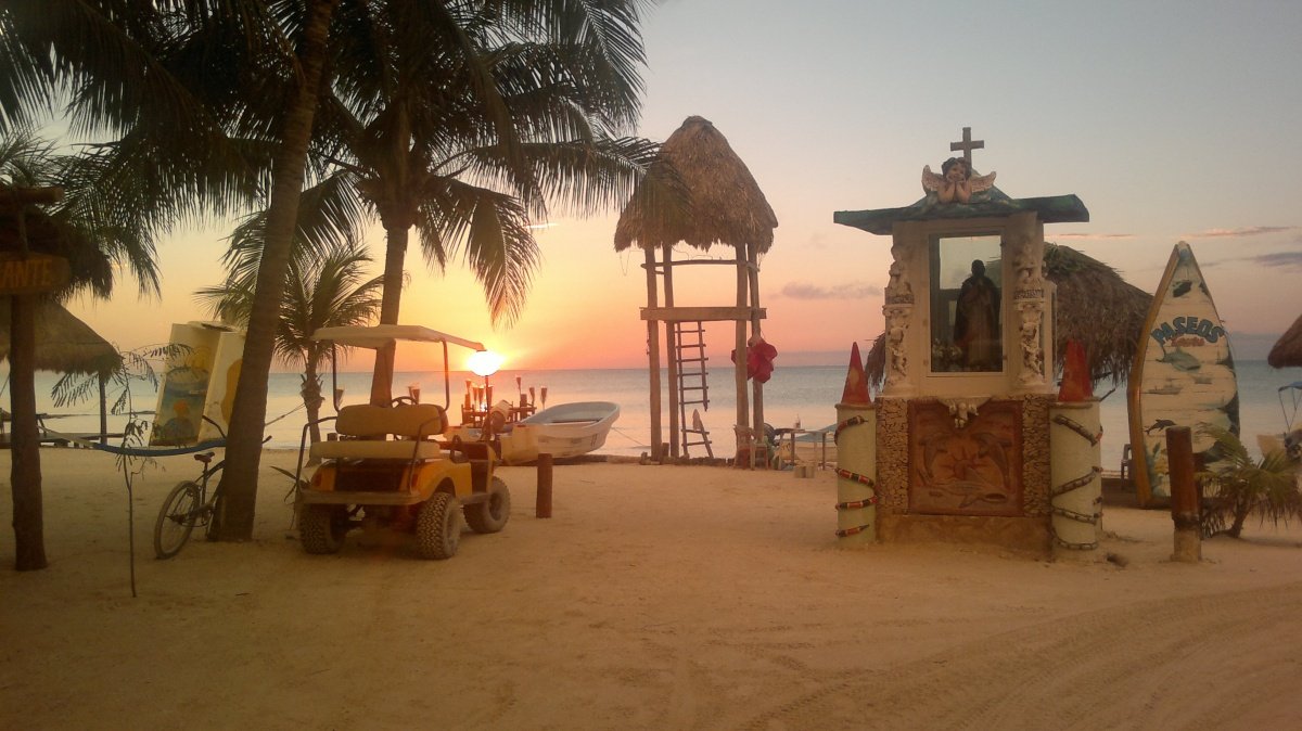 Terreno en venta en isla holbox - Playa al atardecer con palmeras, carrito de golf y torre de vigilancia frente al mar