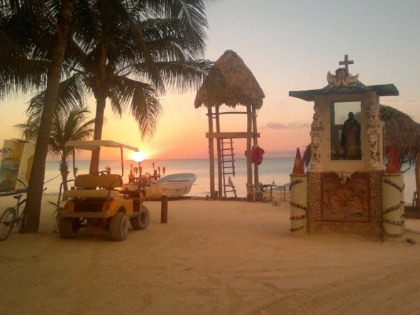 Terreno en venta en isla holbox - Playa al atardecer con palmeras, carrito de golf y torre de vigilancia frente al mar